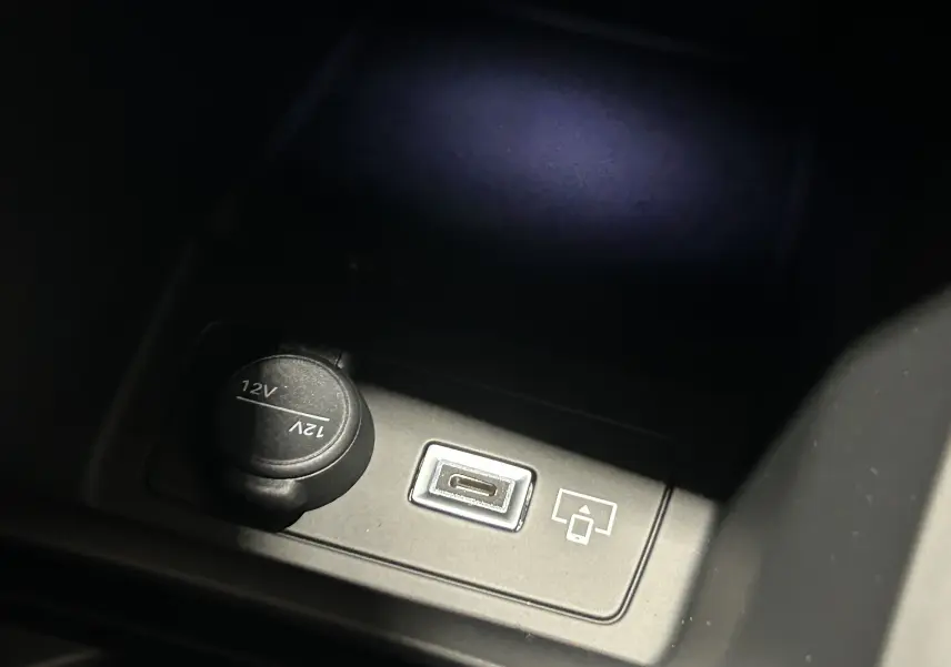 Prise USB et prise 12V en gros plan dans l’espace de rangement central de la Peugeot 308 III Ph.2 Hybrid 145 GT gris Selenium.