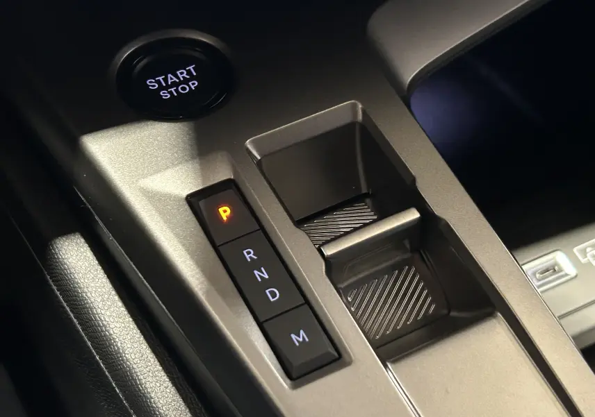 Gros plan sur la console centrale de la Peugeot 308 HYBRID 145 GT avec bouton start/stop et sélection de boîte auto en mode parking.
