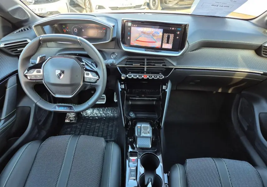 Vue intérieure frontale du poste de conduite de la Peugeot 208 Hybrid 136 GT avec volant compact et écran tactile central.