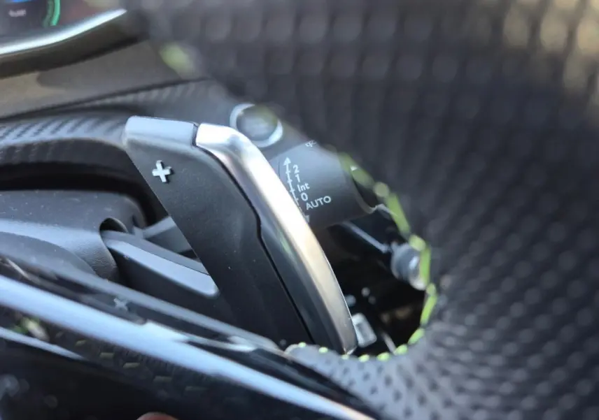Gros plan sur la palette de changement de vitesse + au volant perforé d’une Peugeot 208 Hybrid 136 e-DCS6 GT.