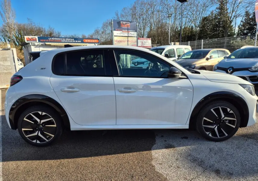 Profil droit de la Peugeot 208 Hybrid 136 GT blanche avec jantes alliage 17 pouces et logo GT sur aile arrière.