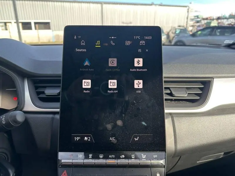 Écran tactile central du tableau de bord du Renault Captur 2025, avec commandes multimédia et climatisation visibles.