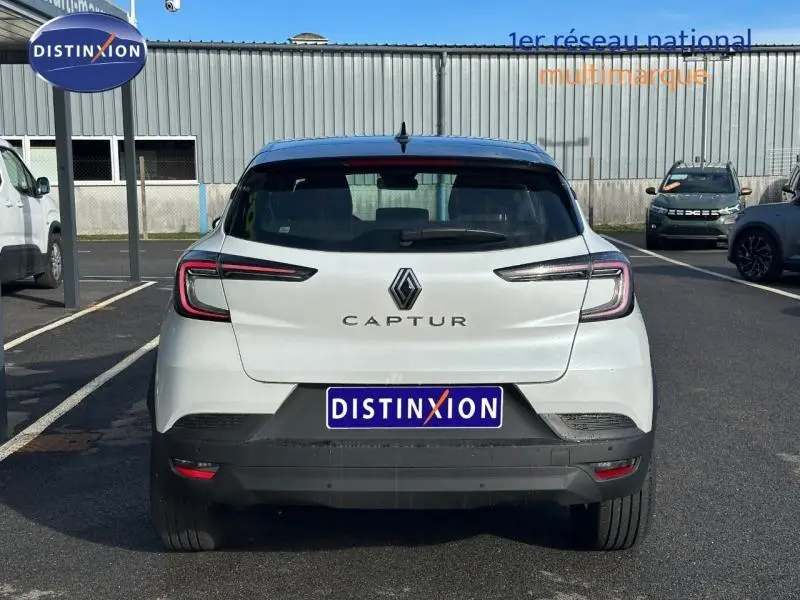 Vue arrière d'un Renault Captur blanc nacré avec toit noir, feux arrière LED et logo central bien visible.