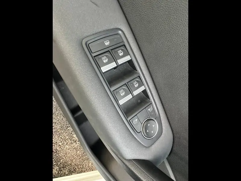 Gros plan sur les commandes des vitres électriques et des rétroviseurs côté conducteur du Renault Captur blanc nacré/noir.