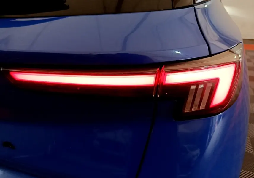 Feu arrière droit allumé sur Opel Mokka bleu, vue rapprochée du coffre et de la lunette arrière.