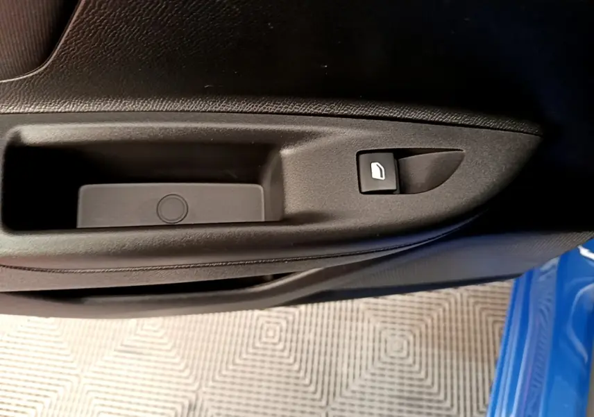 Détail de la commande de lève-vitre sur la porte côté conducteur d’un Opel Mokka bleu 2024.
