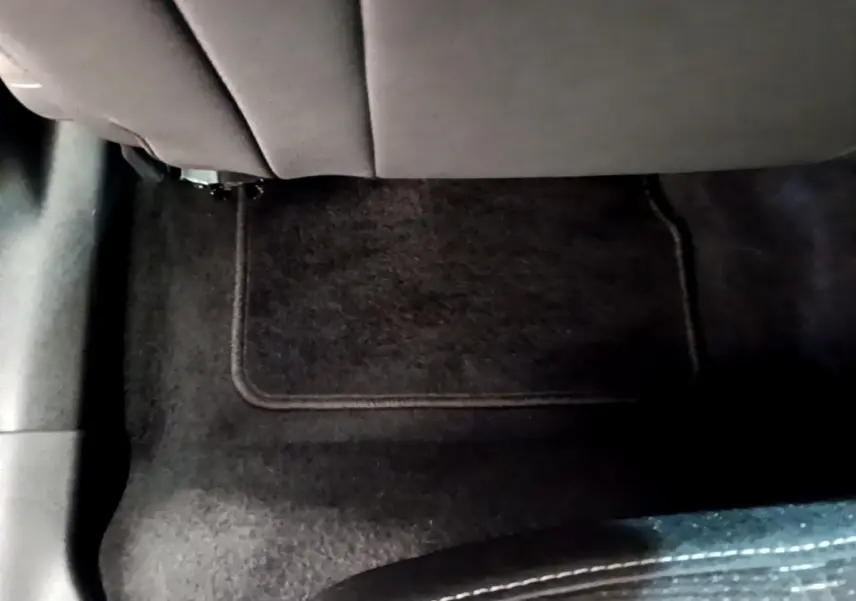 Vue intérieure du sol arrière avec tapis noir sous le siège arrière de l'Opel Mokka 2024 bleu.