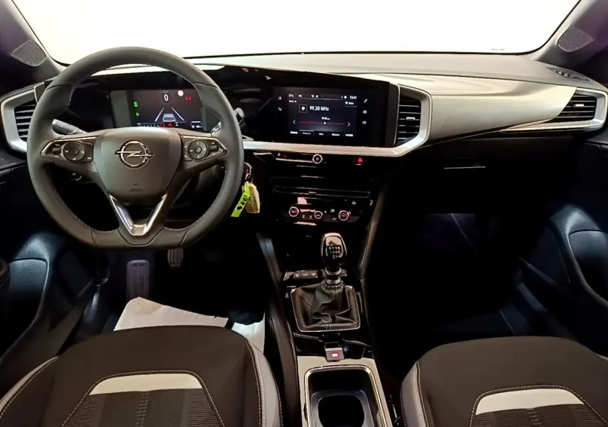 Vue intérieure avant de l’Opel Mokka 2024, tableau de bord noir avec écran tactile et volant multifonctions cuir.