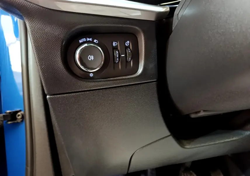 Gros plan sur le panneau de commande des feux à gauche du volant dans l’habitacle bleu d’un Opel Mokka 2024.