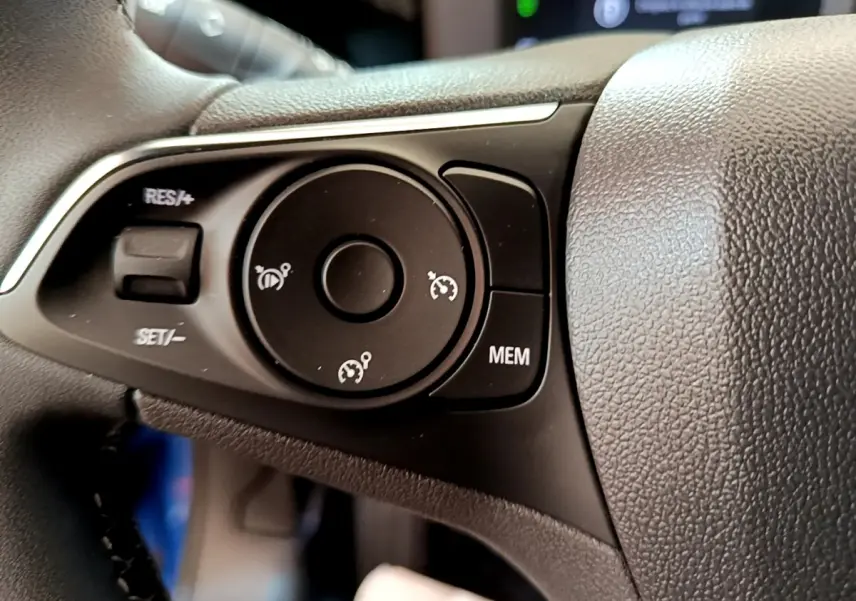 Gros plan sur les commandes du régulateur de vitesse au volant cuir de l’Opel Mokka 2024, intérieur noir.