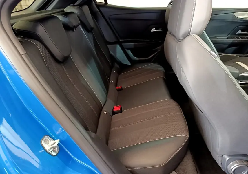 Vue intérieure côté arrière gauche de l’Opel Mokka bleu 2024, montrant la banquette arrière noire avec surpiqûres contrastées.