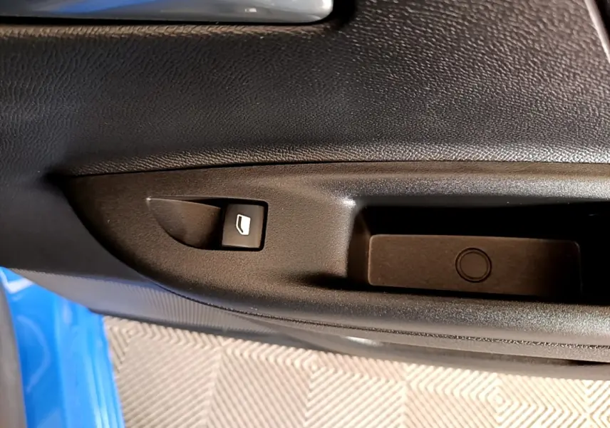 Détail de la commande de lève-vitre sur la porte côté conducteur d’un Opel Mokka bleu 2024.