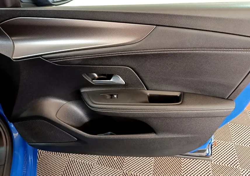 Vue rapprochée de la porte avant gauche de l’Opel Mokka bleu 2024 avec garniture noire et poignée argentée.
