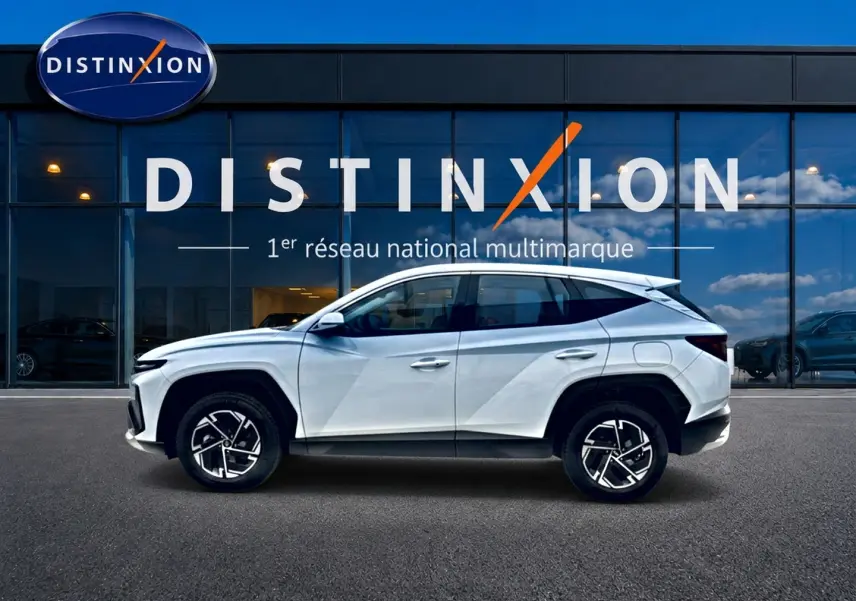 Hyundai Tucson 2026 blanc en profil droit devant une vitrine avec logo Distinxion visible.