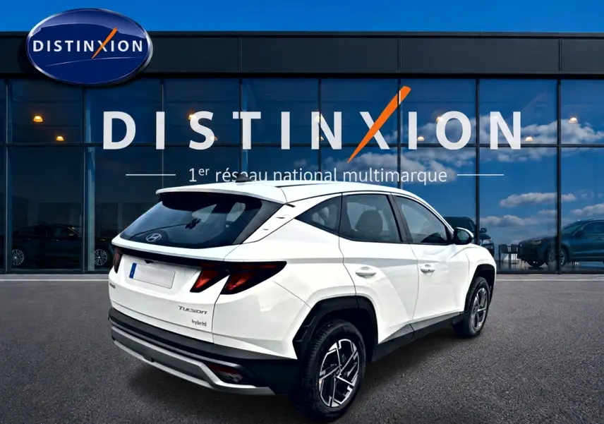 Vue 3/4 arrière droite du Hyundai Tucson blanc hybride 2026 avec jantes alliage et feux arrière LED distinctifs.