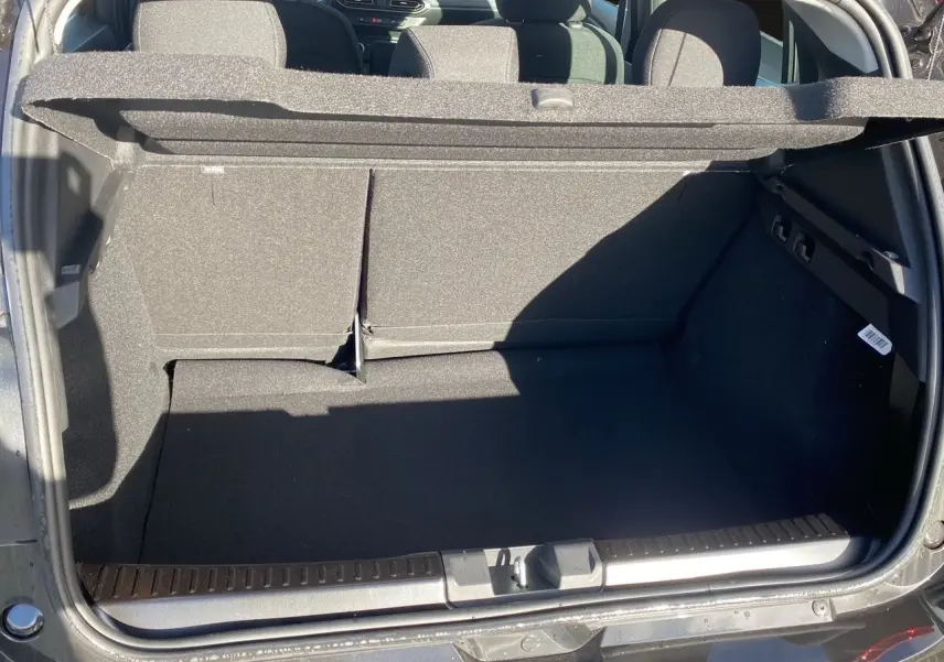 Coffre ouvert vu de l'arrière d'une Dacia Sandero Stepway noire, montrant l'espace de chargement et la banquette arrière.