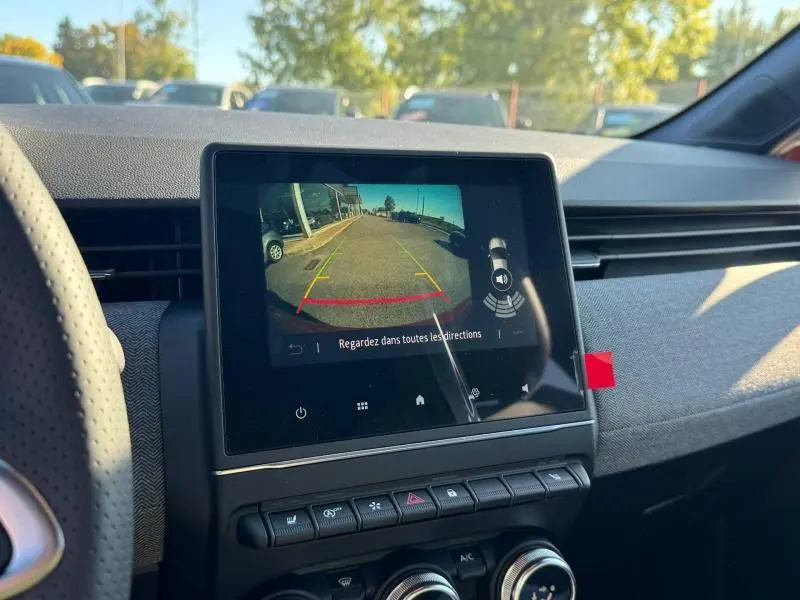 Vue intérieure du tableau de bord de la Renault Clio orange 2025 avec écran tactile affichant la caméra de recul.
