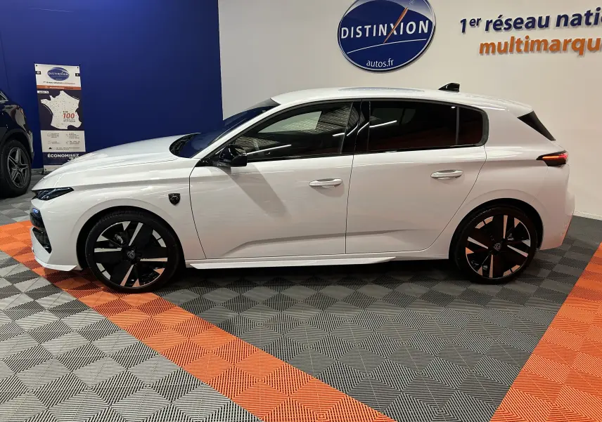 Vue latérale droite d'une Peugeot 308 III Ph.2 HYBRID 145 GT blanche Okenite avec jantes noires et vitres teintées.