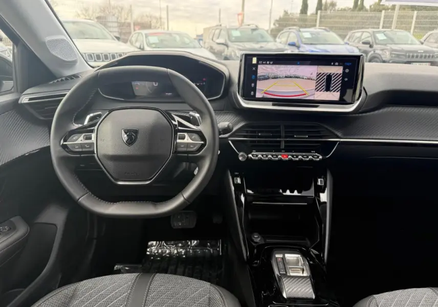 Vue intérieure frontale du cockpit numérique et volant cuir noir de la Peugeot 208 Hybrid 145 Allure 2025, avec écran tactile central.