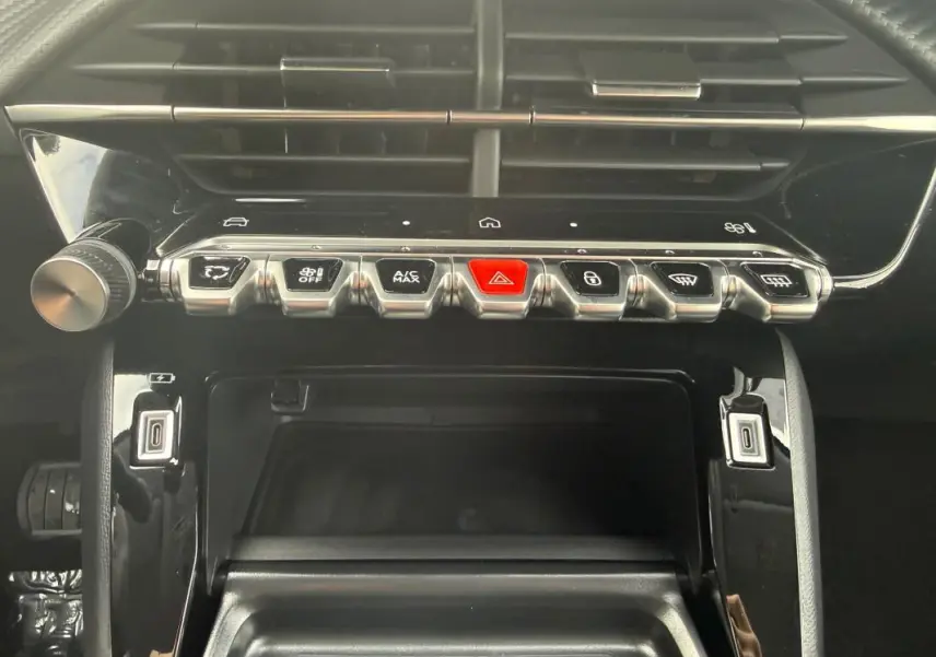 Vue rapprochée du tableau de bord de la Peugeot 208 gris, mettant en valeur les commandes centrales et la ventilation.