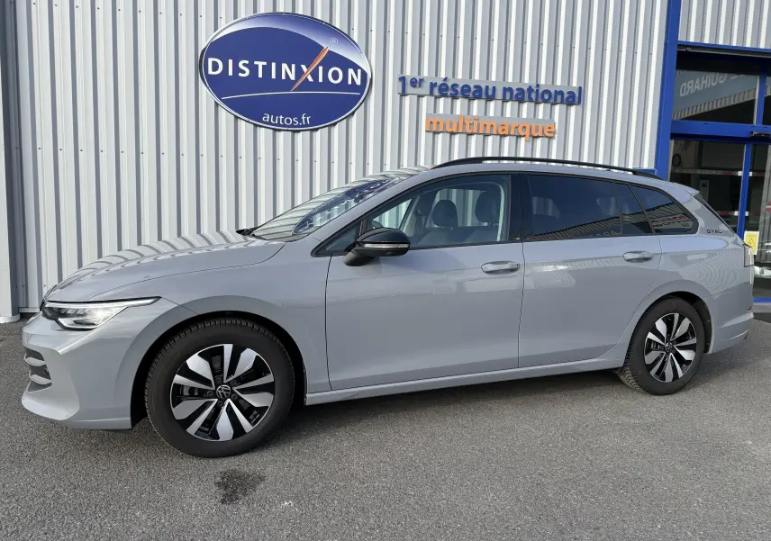 Volkswagen Golf SW 2.0 TDI gris lunaire vue 3/4 avant droit, devant un bâtiment avec enseigne Distinxion.