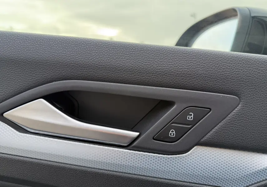 Poignée intérieure côté gauche de la porte d’une Volkswagen Golf SW gris lunaire avec boutons de verrouillage.