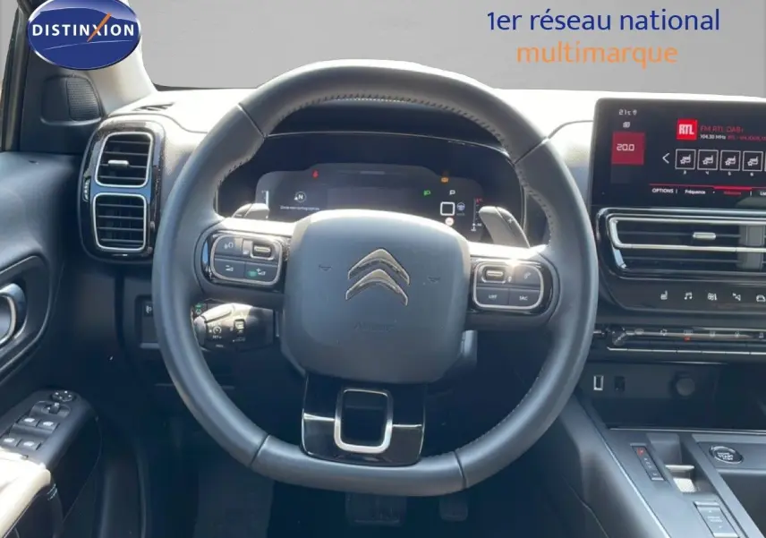 Vue intérieure centrée sur le volant cuir noir du Citroën C5 Aircross 2025 avec tableau de bord digital et écran tactile.