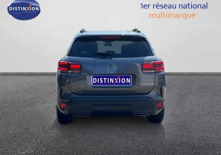 Vue arrière d'un Citroën C5 Aircross gris platinium métal avec feux arrière allumés sur fond neutre.