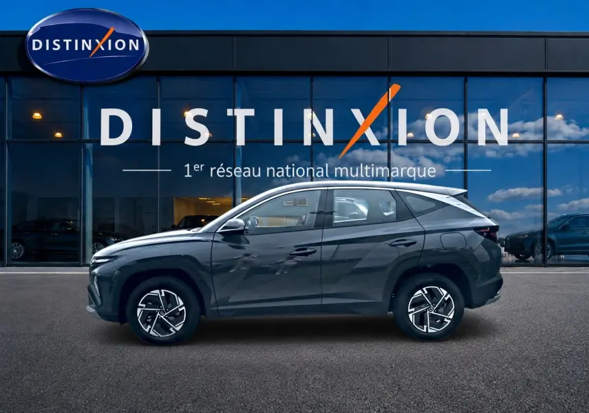 Hyundai Tucson 1.6 t-gdi 239 hybride gris ecotronique vu de profil côté gauche devant une vitrine Distinxion.