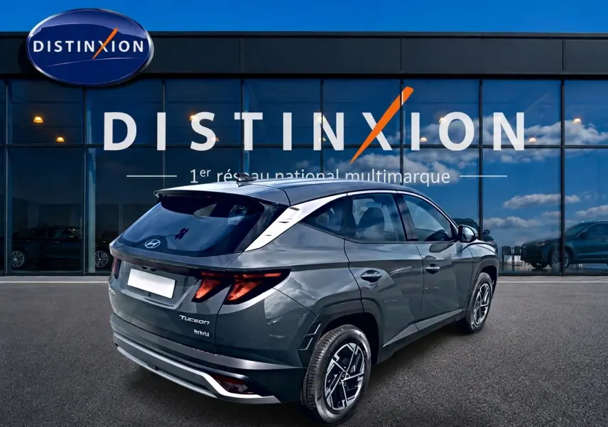 Vue 3/4 arrière droite du Hyundai Tucson gris écotronique avec jantes alliage et toit noir devant une vitrine Distinxion.