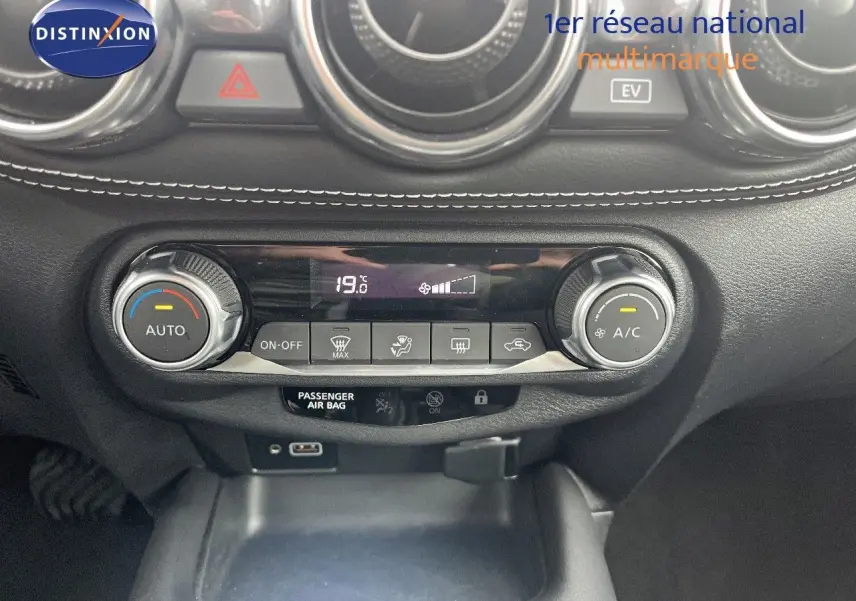 Détail de la console centrale du Nissan Juke blanc nacré 2024, mettant en valeur la climatisation automatique et les commandes digitales.
