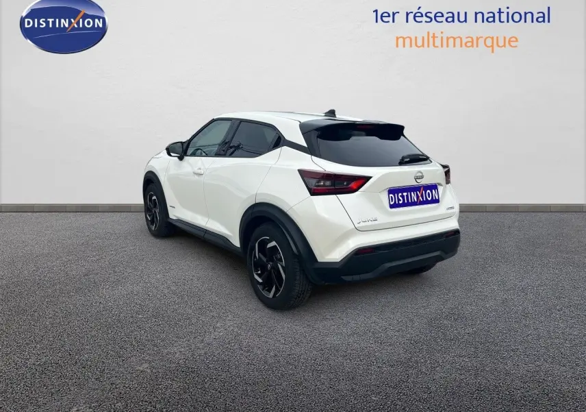 Nissan Juke blanc nacré métal vu de trois quarts arrière côté gauche, avec jantes noires et toit noir contrasté.