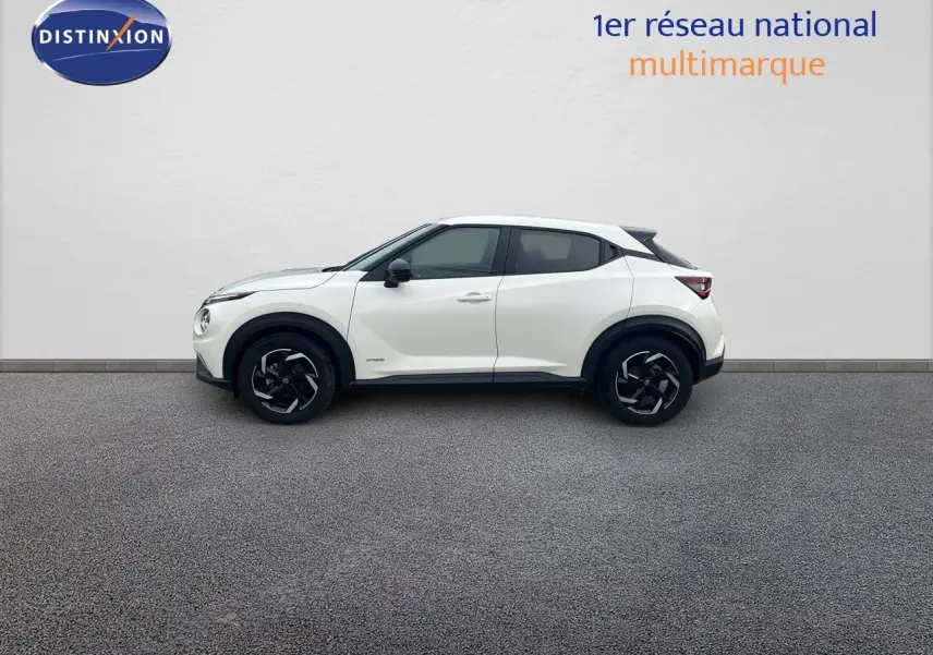 Profil côté gauche du Nissan Juke blanc nacré 2024 avec jantes noires et toit contrasté noir.