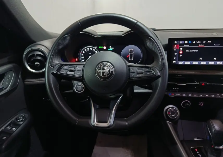 Vue frontale du volant cuir noir de l'Alfa Romeo Tonale 2023 avec tableau de bord digital et écran tactile central.