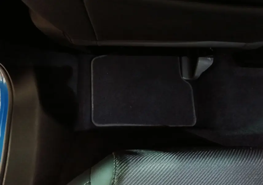 Vue intérieure du plancher côté passager avant avec tapis noir et partie de la portière bleue d’un Alfa Romeo Tonale 2023.