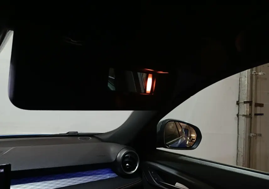 Intérieur côté passager de l'Alfa Romeo Tonale bleu, avec tableau de bord et rétroviseur latéral visible.