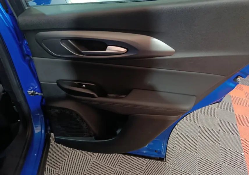 Vue rapprochée de la porte arrière gauche bleu vif de l'Alfa Romeo Tonale avec poignée intérieure argentée.