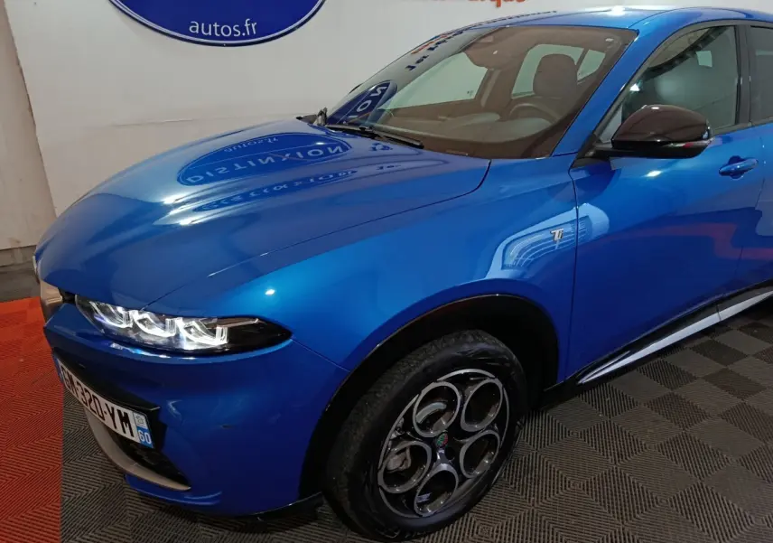 Vue 3/4 avant droit de l'Alfa Romeo Tonale bleu avec jantes distinctives et badge Ti sur l'aile avant.