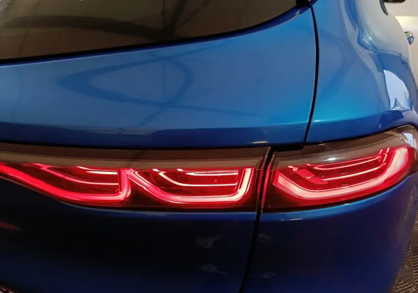 Gros plan sur le feu arrière droit rouge vif d'une Alfa Romeo Tonale hybride rechargeable bleu métallisé.