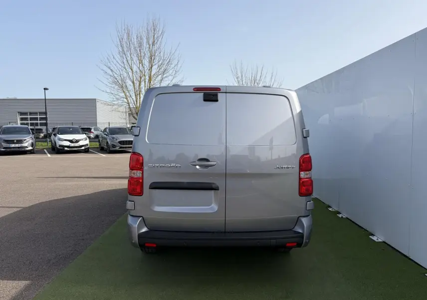 Vue arrière d'un Citroën Jumpy gris acier métal stationné, avec portes battantes et feux rouges verticaux.