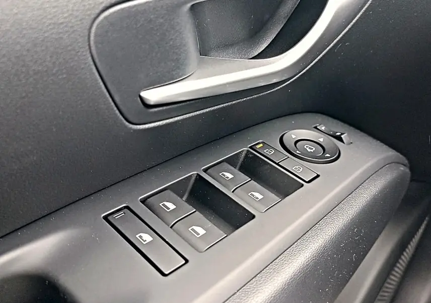 Gros plan sur les commandes de vitres électriques et rétroviseurs côté gauche du Hyundai Tucson gris Ecotronique 2026.