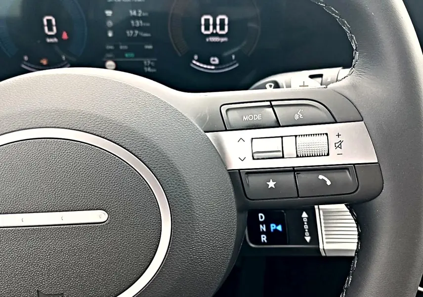 Gros plan sur le volant cuir multifonction du Hyundai Tucson gris, avec commandes audio et affichage numérique du tableau de bord.