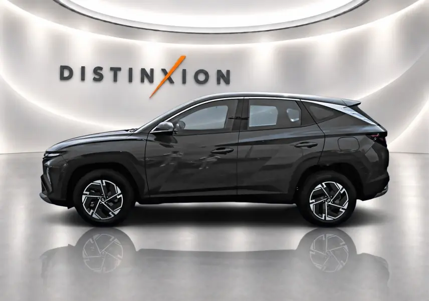 Vue de profil côté gauche du Hyundai Tucson 2026 gris ecotronique avec jantes alliage et rétroviseurs ton carrosserie.
