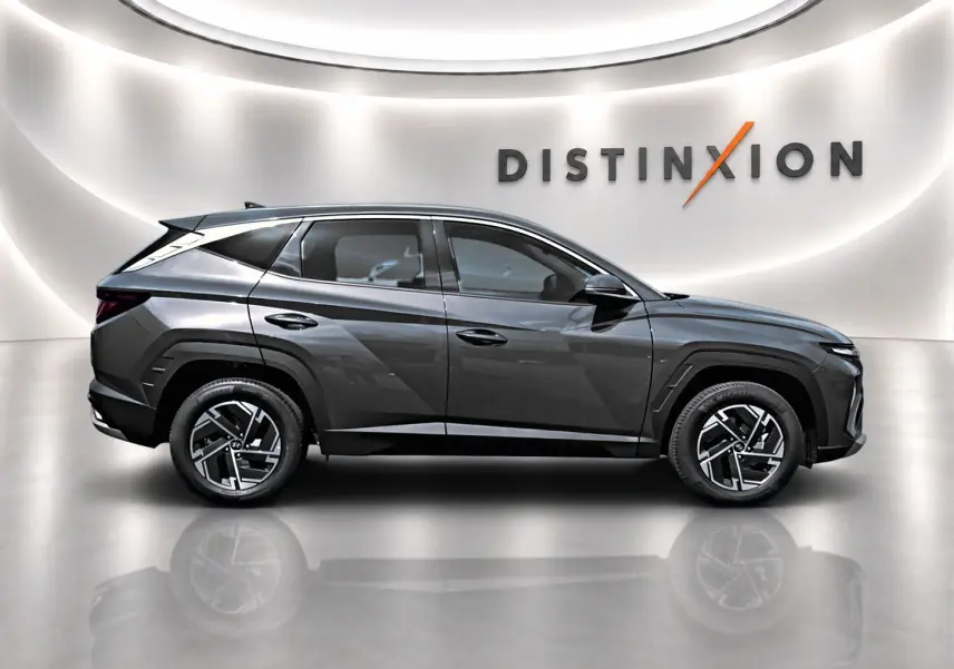 Vue de profil côté gauche du Hyundai Tucson 2026 gris ecotronique avec jantes alliage 17 pouces dans un showroom lumineux.