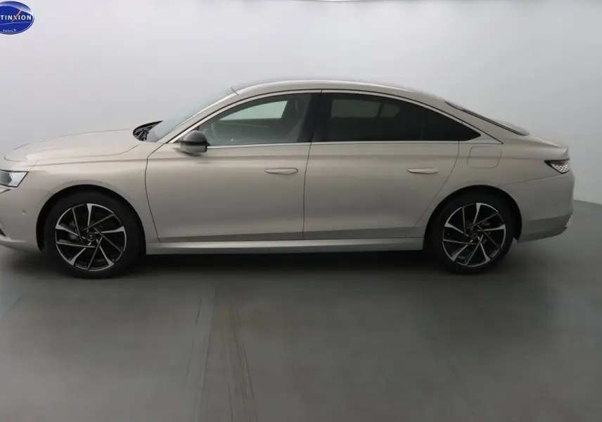 Profil côté gauche de la berline DS9 hybride rechargeable 2022 en couleur Crystal Pearl nacré métal avec jantes noires et argentées.