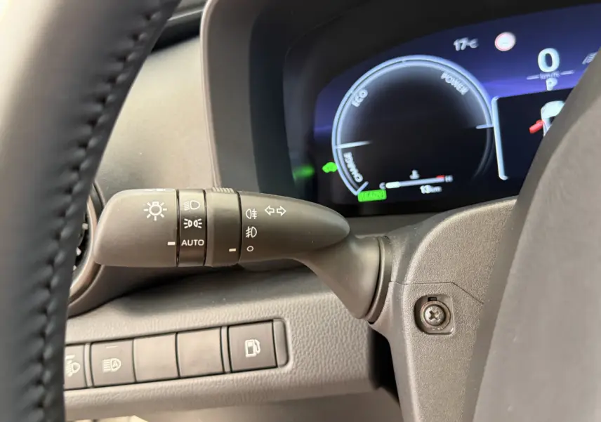 Détail du commodo d'éclairage côté gauche avec tableau de bord numérique bleu du Toyota C-HR 1.8 Hybride blanc 2024.