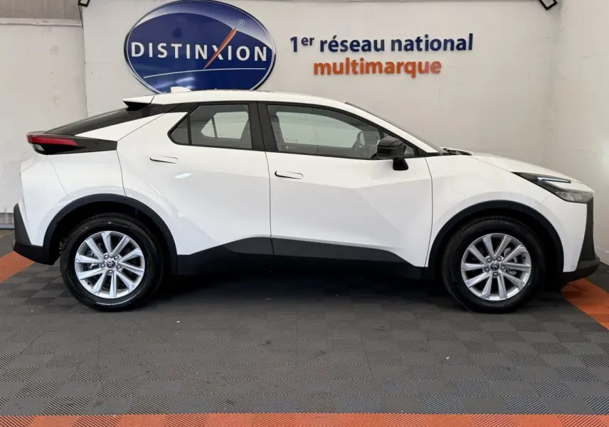 Profil côté droit d’un Toyota C-HR blanc 2024 avec jantes alliage et détails noirs contrastants sur les bas de caisse.