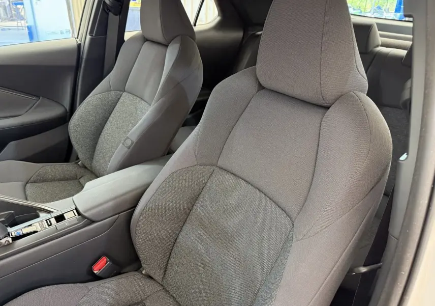Vue rapprochée des sièges avant gris du Toyota C-HR 1.8 Hybride 140 Dynamic avec accoudoir central.