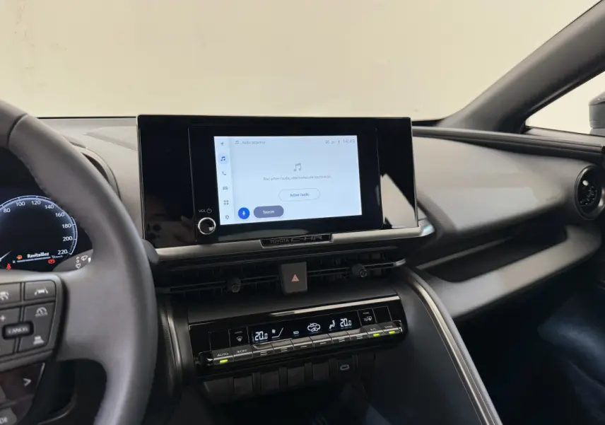 Vue intérieure du tableau de bord du Toyota C-HR 1.8 Hybride 2024 avec écran tactile central et commandes climatisation digitales.
