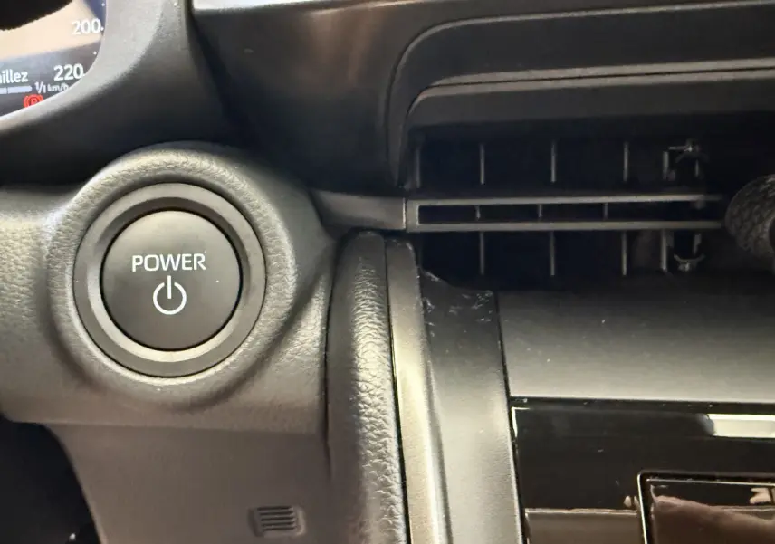 Bouton Power rond noir sur tableau de bord noir du Toyota C-HR 1.8 Hybride 140 Dynamic 2024, vue intérieure proche.